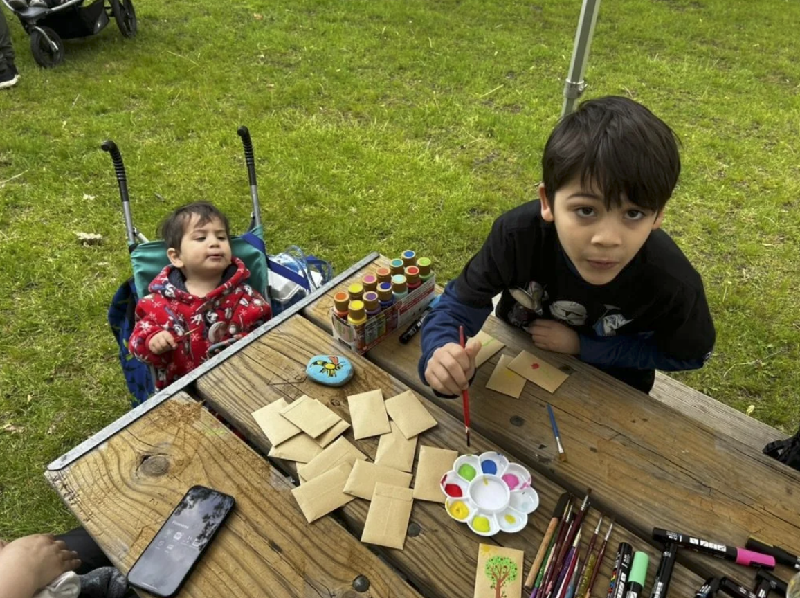 Children showing painted rocks at the event table